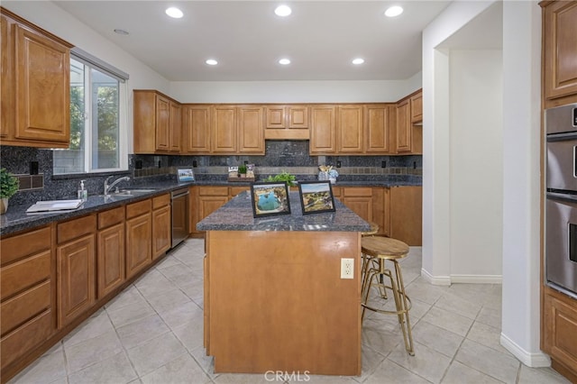 kitchen featuring a center island, a kitchen bar, dark stone countertops, appliances with stainless steel finishes, and brown cabinetry