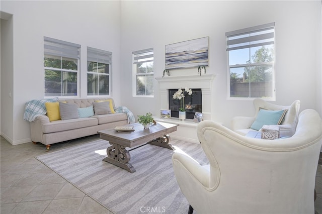 living room featuring a glass covered fireplace, baseboards, and tile patterned flooring