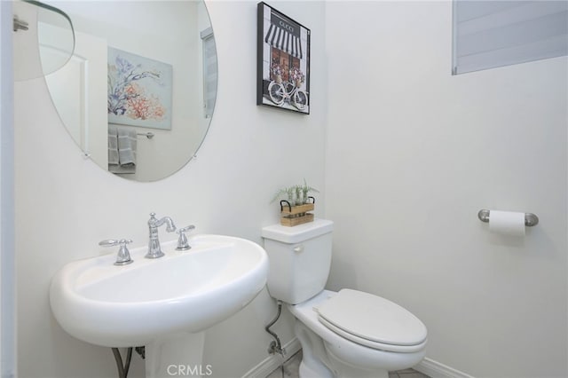 bathroom featuring toilet, baseboards, and a sink