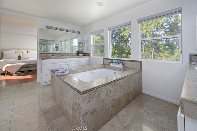 ensuite bathroom featuring ensuite bathroom, tile patterned flooring, baseboards, a bath, and vanity