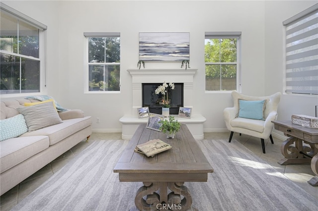 tiled living room featuring baseboards and a warm lit fireplace