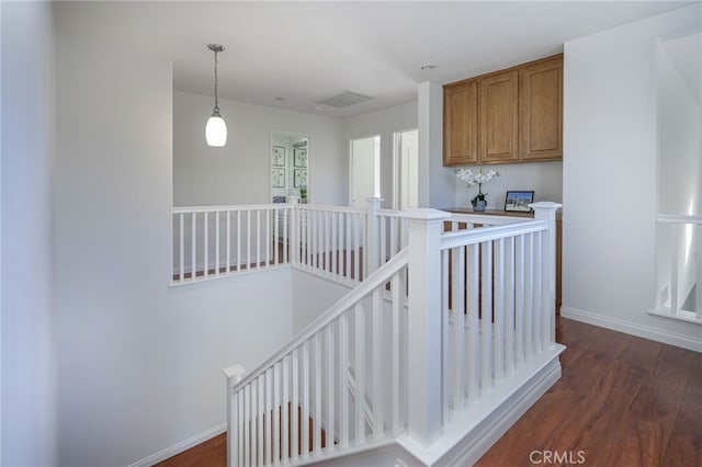 stairway with visible vents, baseboards, and wood finished floors