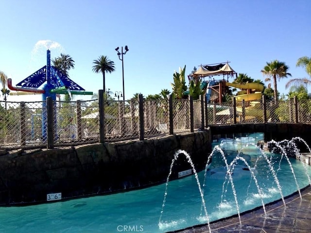 view of swimming pool with playground community and fence