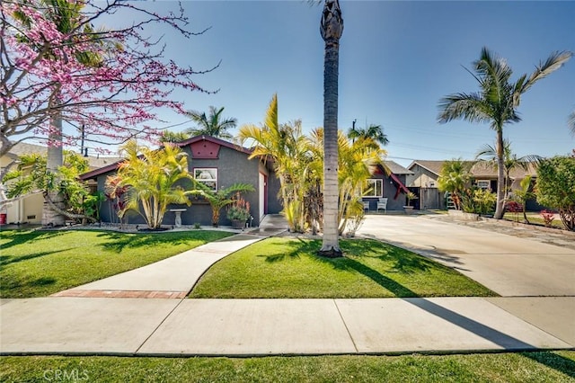 view of front of home featuring a front lawn, concrete driveway, a residential view, and stucco siding