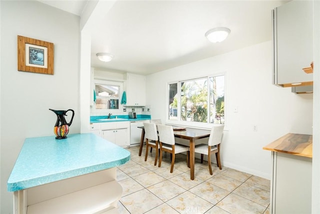 kitchen featuring dishwasher, light countertops, white cabinetry, and a sink