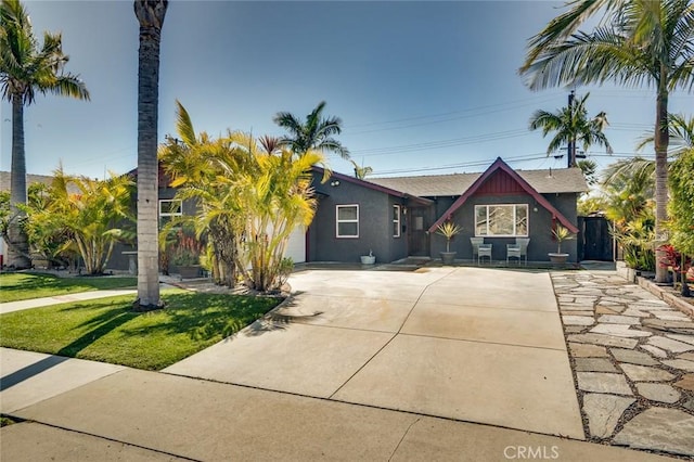 view of front of house with stucco siding, driveway, a garage, and a front yard