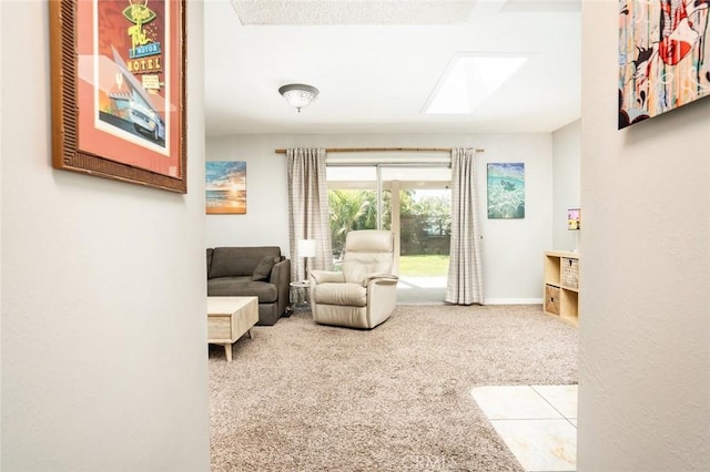 sitting room with a skylight, baseboards, and carpet floors