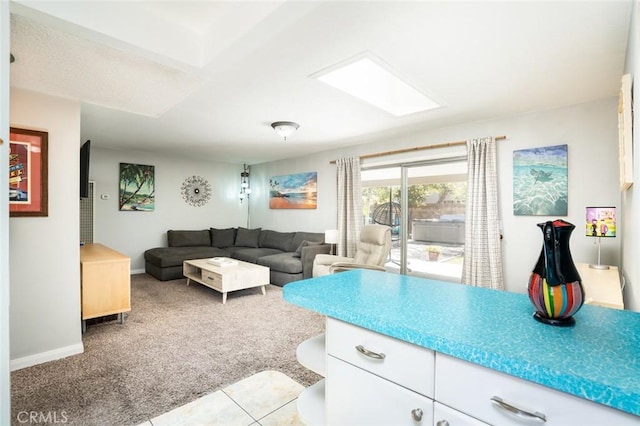 living area featuring light tile patterned floors, baseboards, light carpet, and a skylight