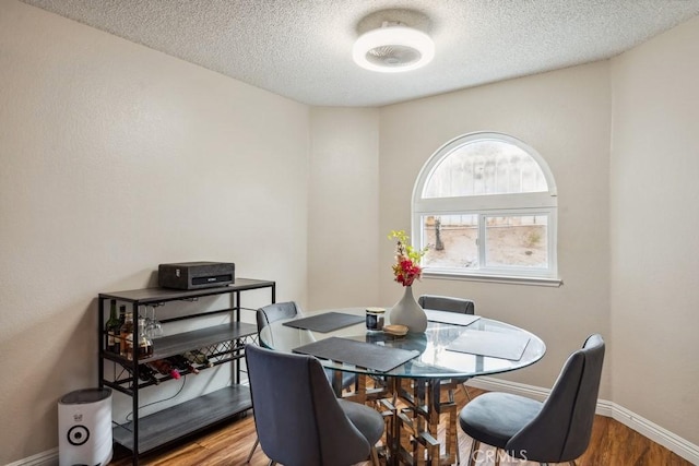 dining area featuring wood finished floors, baseboards, and a textured ceiling