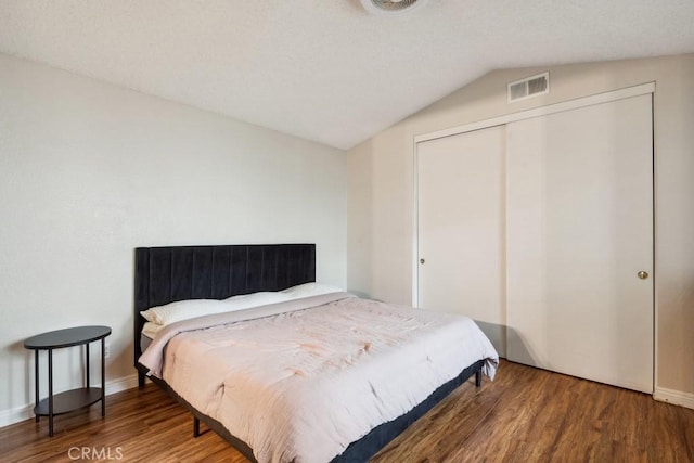 bedroom featuring visible vents, wood finished floors, a closet, baseboards, and vaulted ceiling