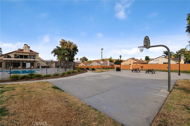 view of basketball court with community basketball court, a fenced in pool, and fence