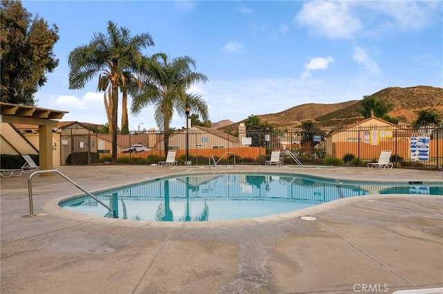 pool featuring a mountain view, a patio area, and fence