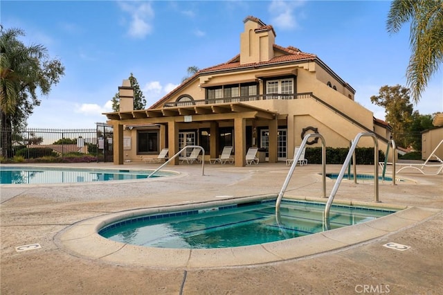 pool featuring a hot tub, a patio, and fence