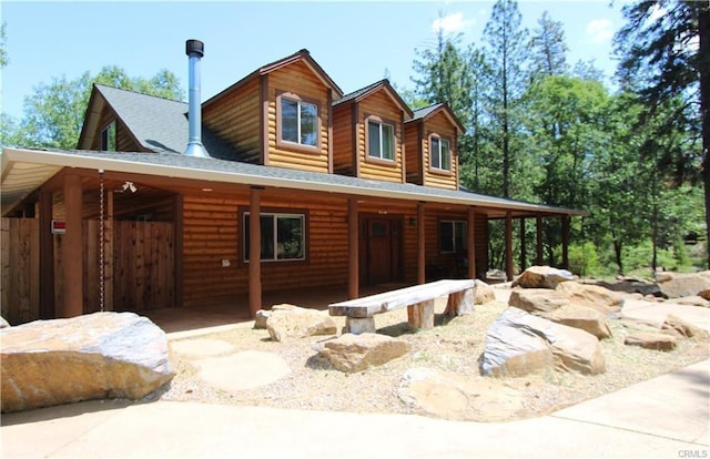 view of front facade featuring a porch, log veneer siding, and roof with shingles