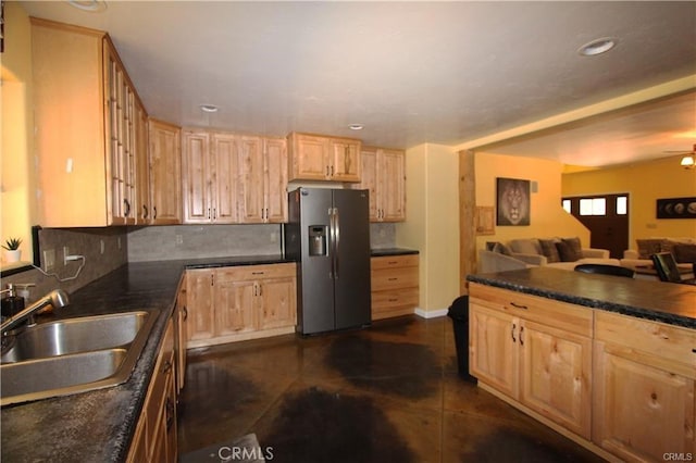 kitchen with light brown cabinetry, a sink, dark countertops, stainless steel fridge with ice dispenser, and decorative backsplash