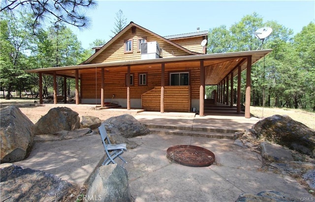 rear view of house featuring covered porch and faux log siding