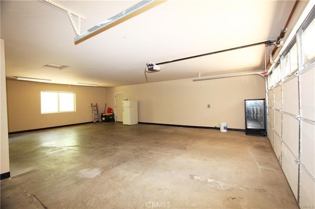 garage featuring a garage door opener, baseboards, and freestanding refrigerator