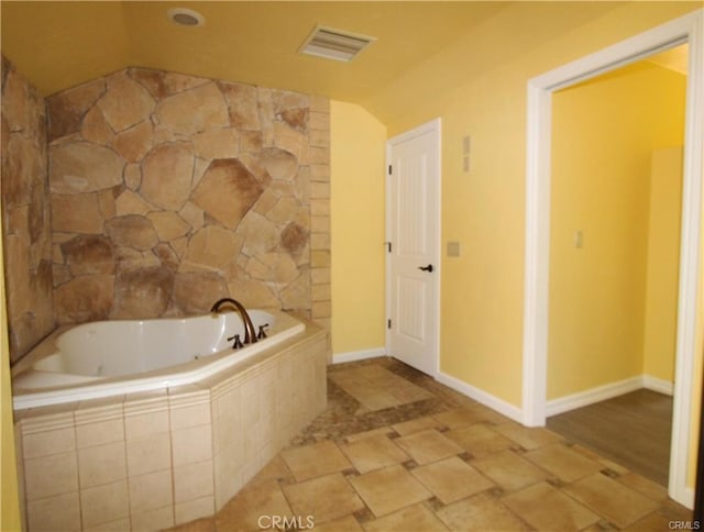 bathroom with visible vents, baseboards, a garden tub, and vaulted ceiling