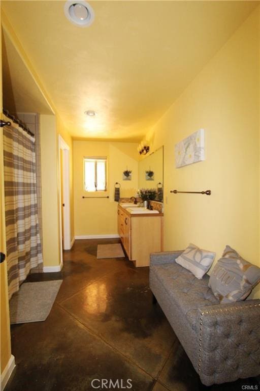 interior space featuring curtained shower, vanity, concrete flooring, and baseboards