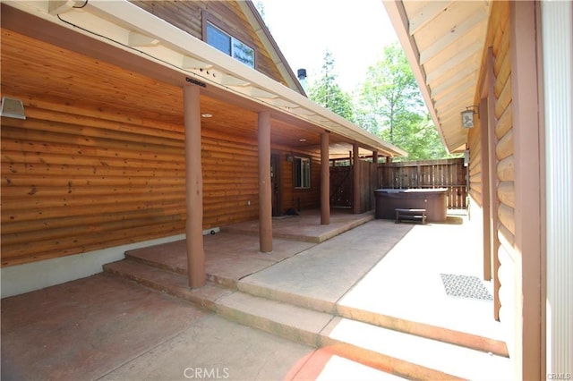 view of patio / terrace featuring a hot tub and fence