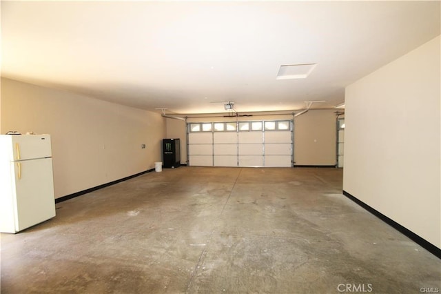 garage featuring baseboards, water heater, and freestanding refrigerator