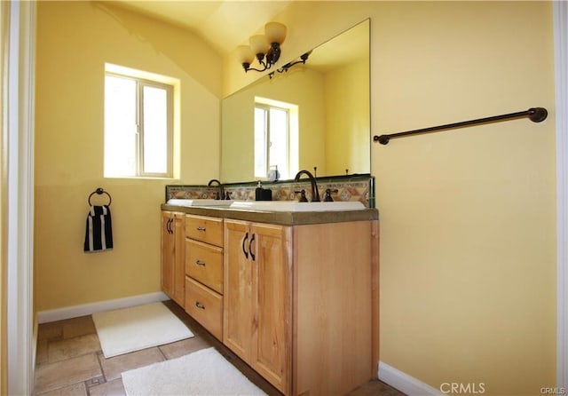 full bathroom featuring a wealth of natural light, a sink, baseboards, and double vanity