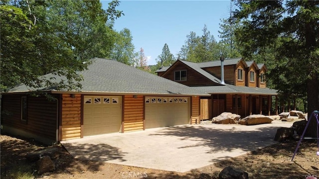 view of front of home featuring log veneer siding, concrete driveway, a garage, and roof with shingles