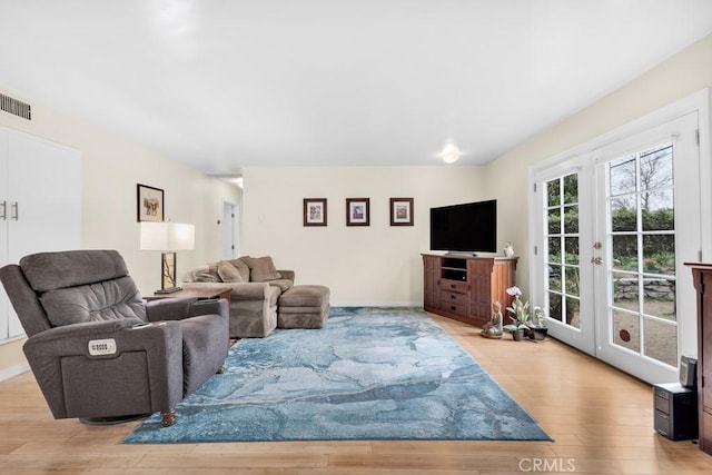 living area with light wood-type flooring, baseboards, and french doors