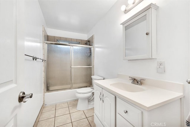 bathroom with bath / shower combo with glass door, toilet, vanity, and tile patterned flooring