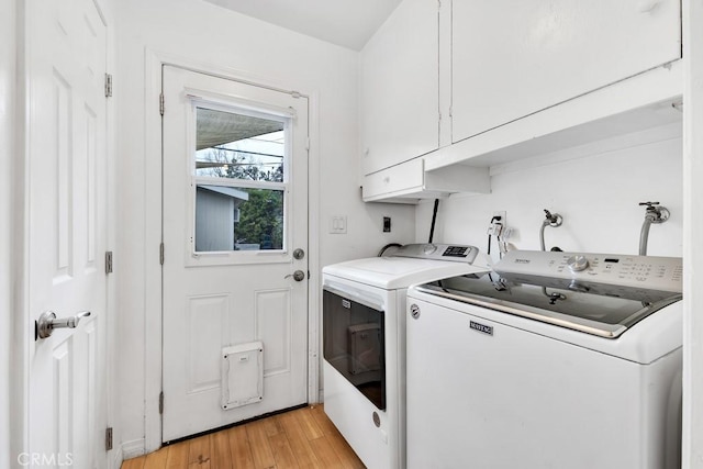 laundry area with cabinet space, washing machine and dryer, and light wood finished floors