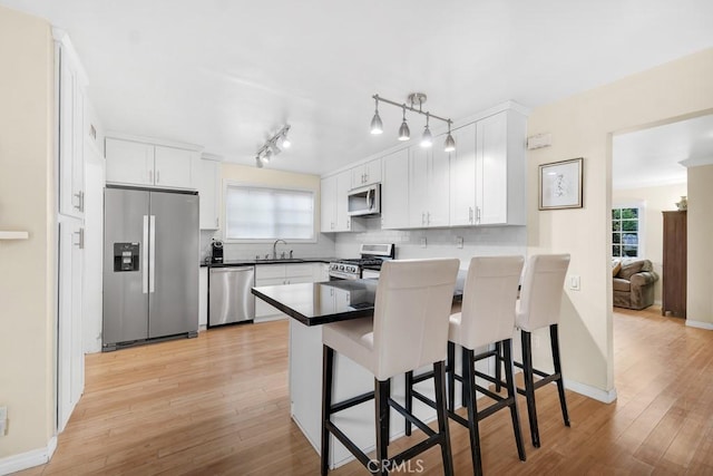 kitchen with white cabinetry, a peninsula, light wood-style floors, and appliances with stainless steel finishes