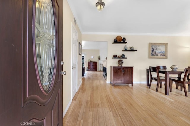 entryway with light wood-style flooring, baseboards, and ornamental molding