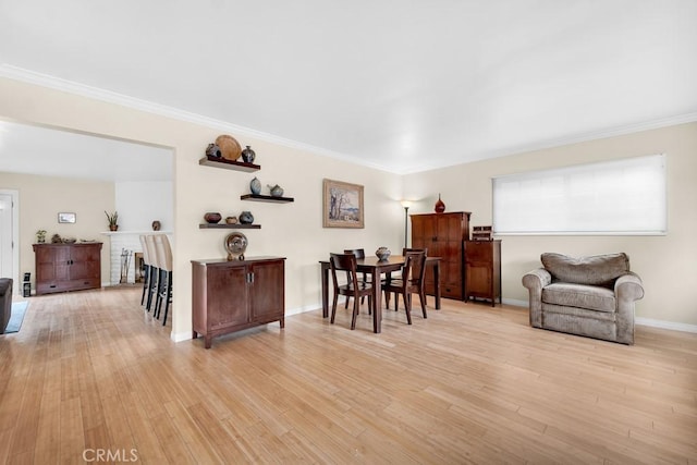 dining space with baseboards, light wood-type flooring, and ornamental molding