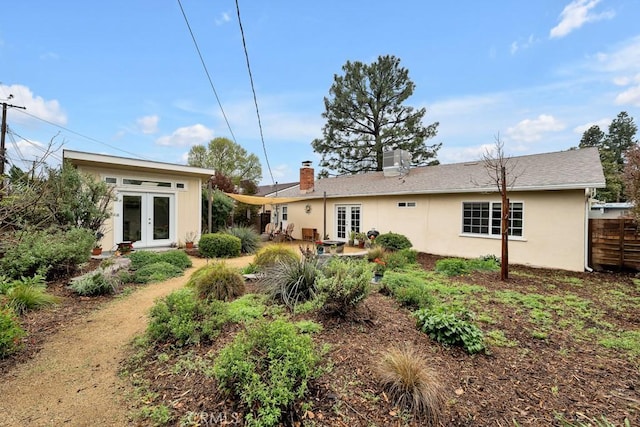 back of house with french doors, a chimney, stucco siding, and fence