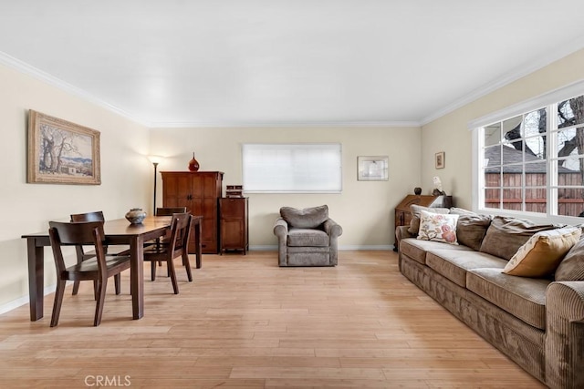 living area featuring crown molding, light wood-type flooring, and baseboards