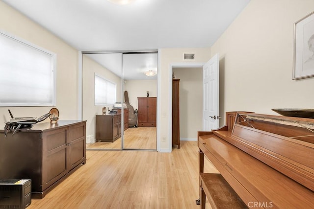 interior space with light wood-style flooring, baseboards, visible vents, and a closet