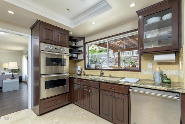 kitchen with a sink, crown molding, appliances with stainless steel finishes, a raised ceiling, and backsplash