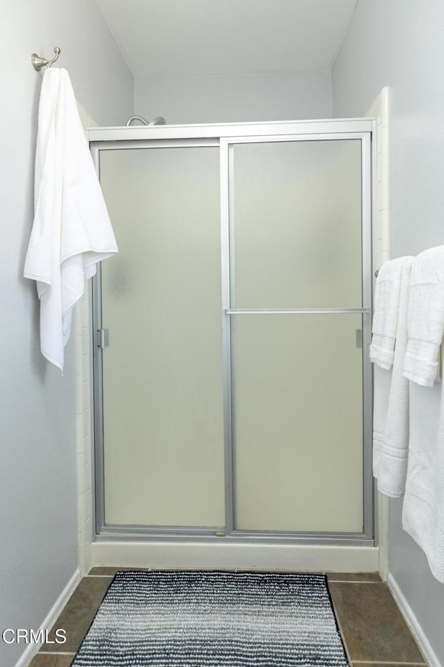 bathroom with tile patterned flooring, a shower stall, and baseboards