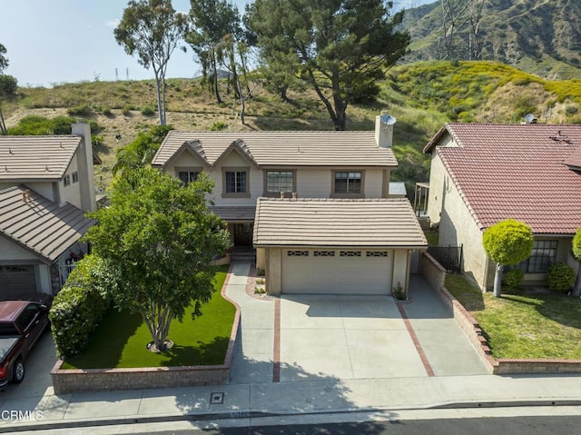 view of front facade featuring a tile roof, stucco siding, concrete driveway, and a chimney