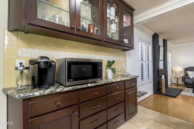 interior space with tasteful backsplash, stainless steel microwave, and crown molding