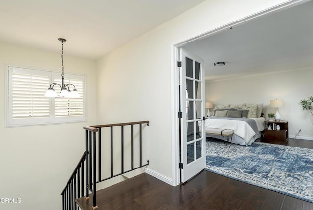 hall featuring dark wood-style floors, a notable chandelier, an upstairs landing, and baseboards