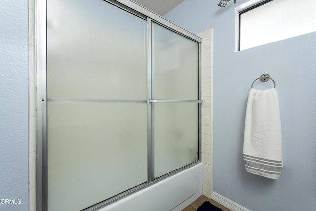 full bathroom featuring combined bath / shower with glass door and baseboards