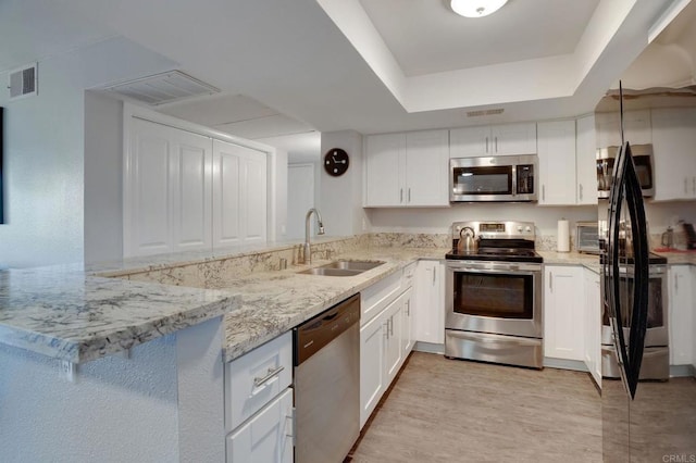 kitchen featuring a sink, a peninsula, visible vents, and stainless steel appliances