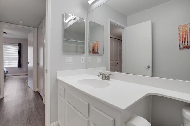 bathroom featuring vanity, wood finished floors, and baseboards