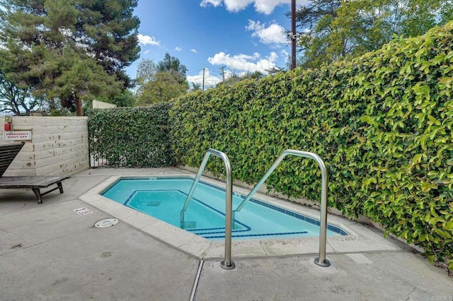 view of swimming pool with a hot tub and fence