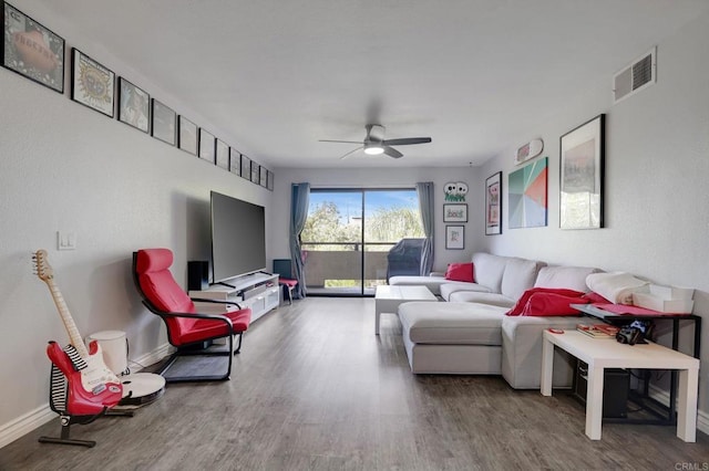 living area with wood finished floors, a ceiling fan, baseboards, and visible vents