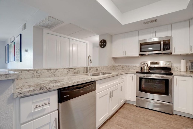 kitchen with visible vents, light wood-style flooring, appliances with stainless steel finishes, white cabinetry, and a sink