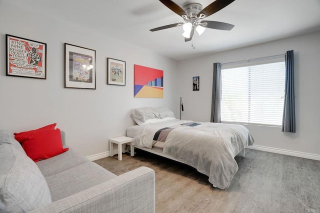 bedroom featuring a ceiling fan, baseboards, and wood finished floors