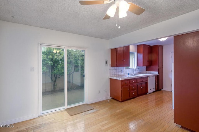 kitchen featuring a ceiling fan, light wood-type flooring, light countertops, dishwasher, and tasteful backsplash