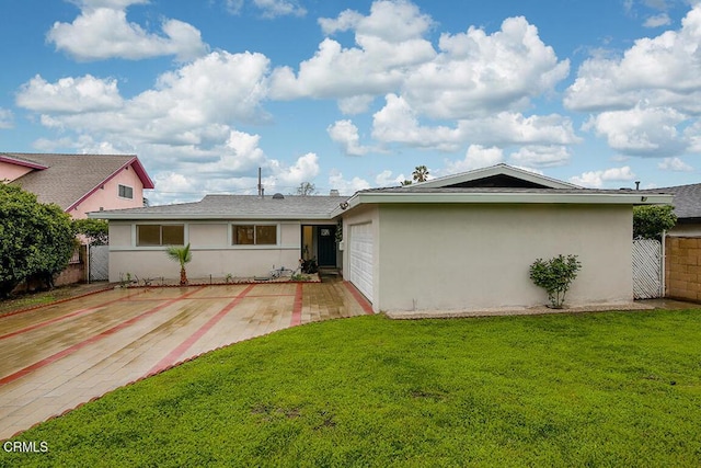 back of house featuring fence, driveway, a yard, an attached garage, and stucco siding